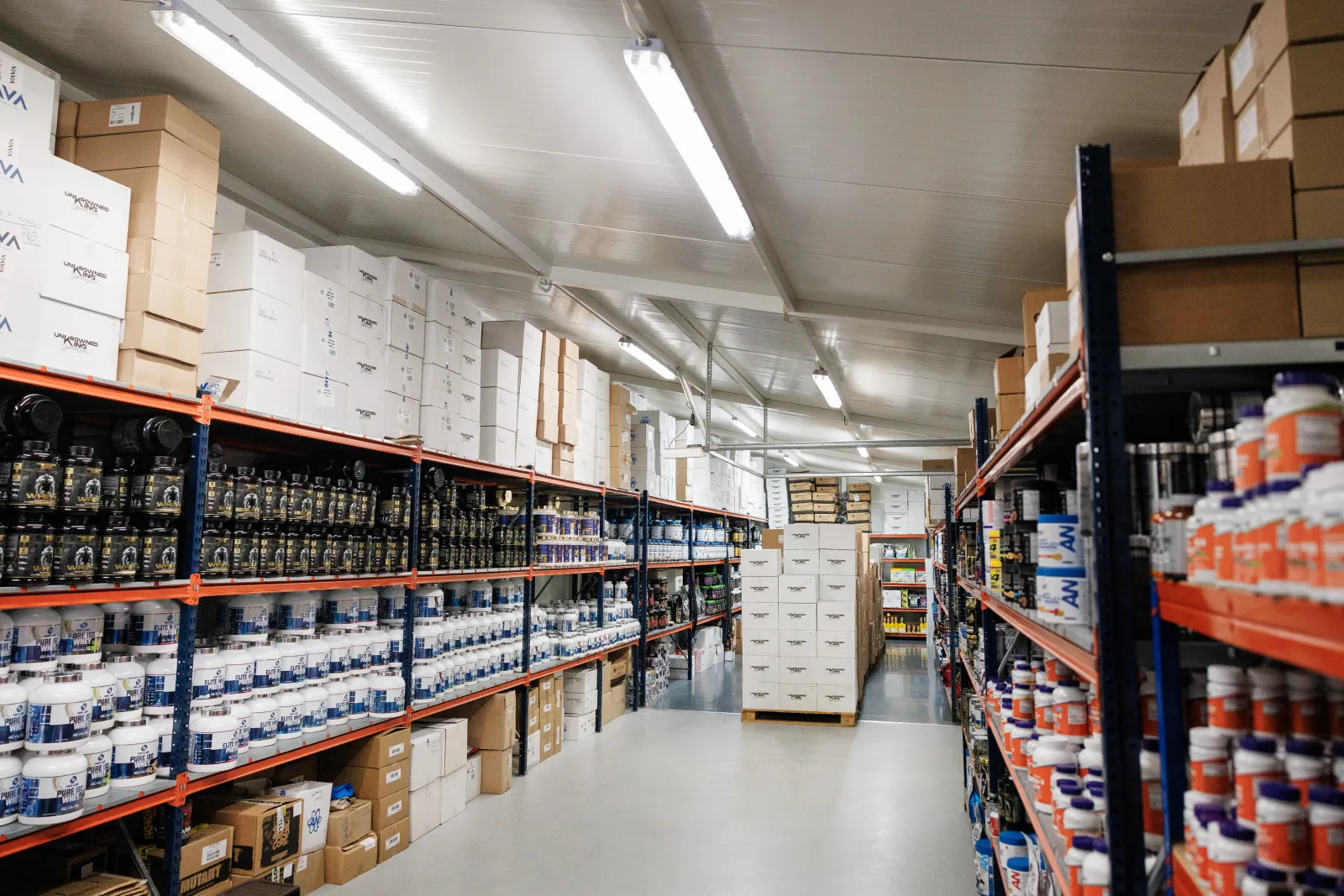 Corredor do armazém GoShape Nutrition com prateleiras de suplementos